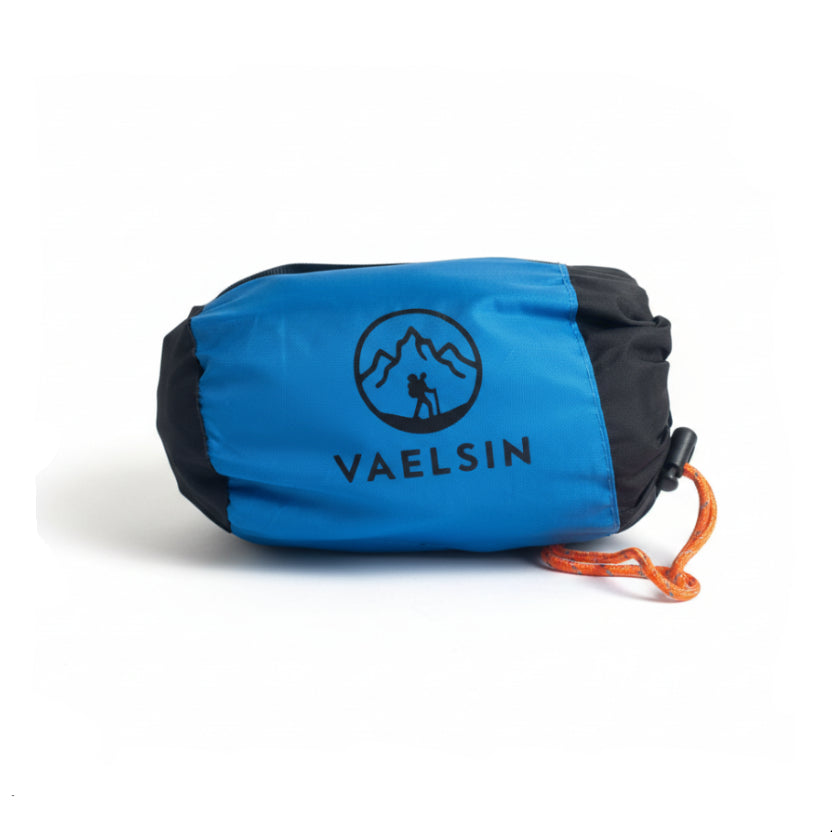 Blue drawstring bag with Vaelsin logo on a beige surface