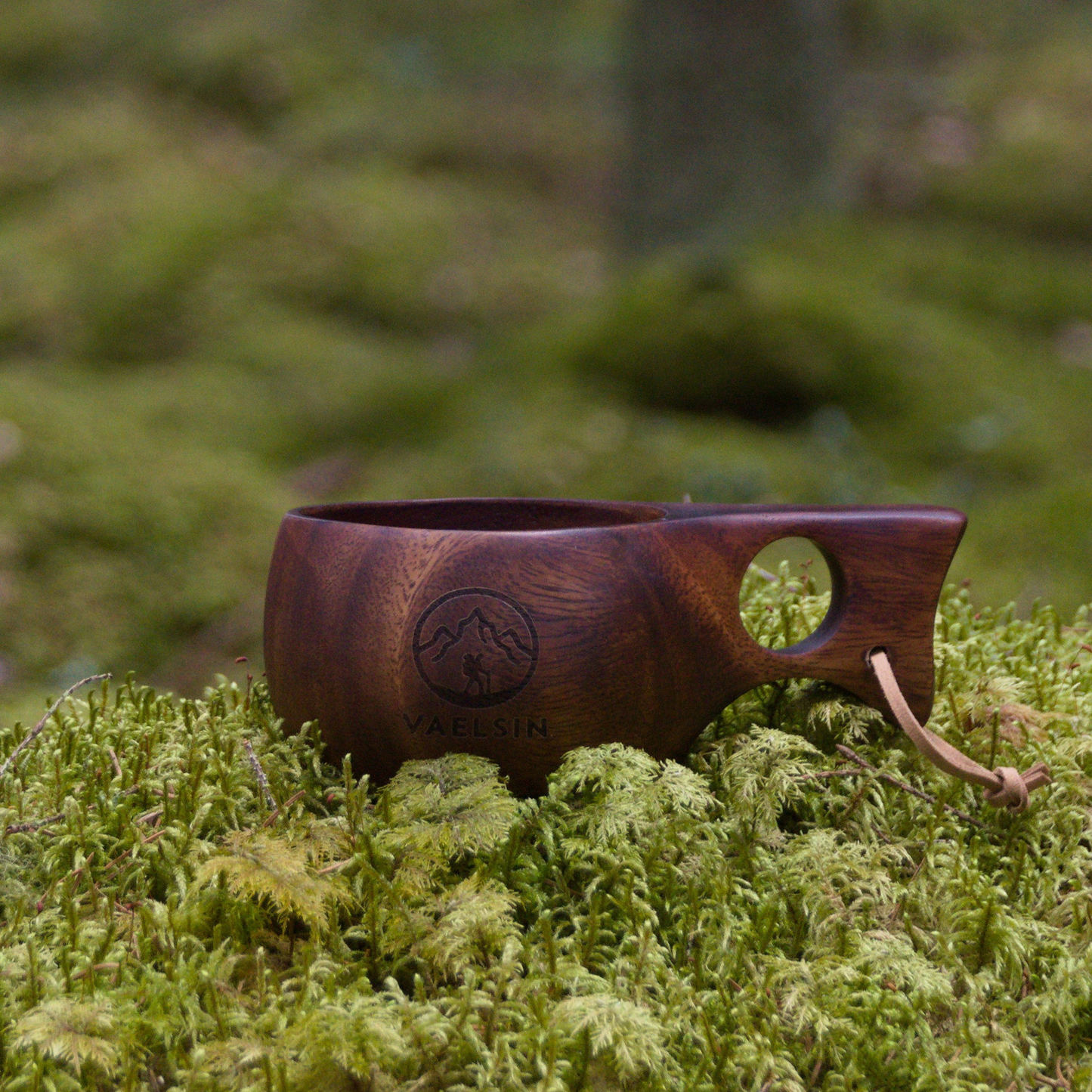 Wooden cup with handle on a mossy ground in a forest setting